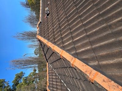 Fresh sand-and-cement bedding being laid under ridgecaps on a tile roof